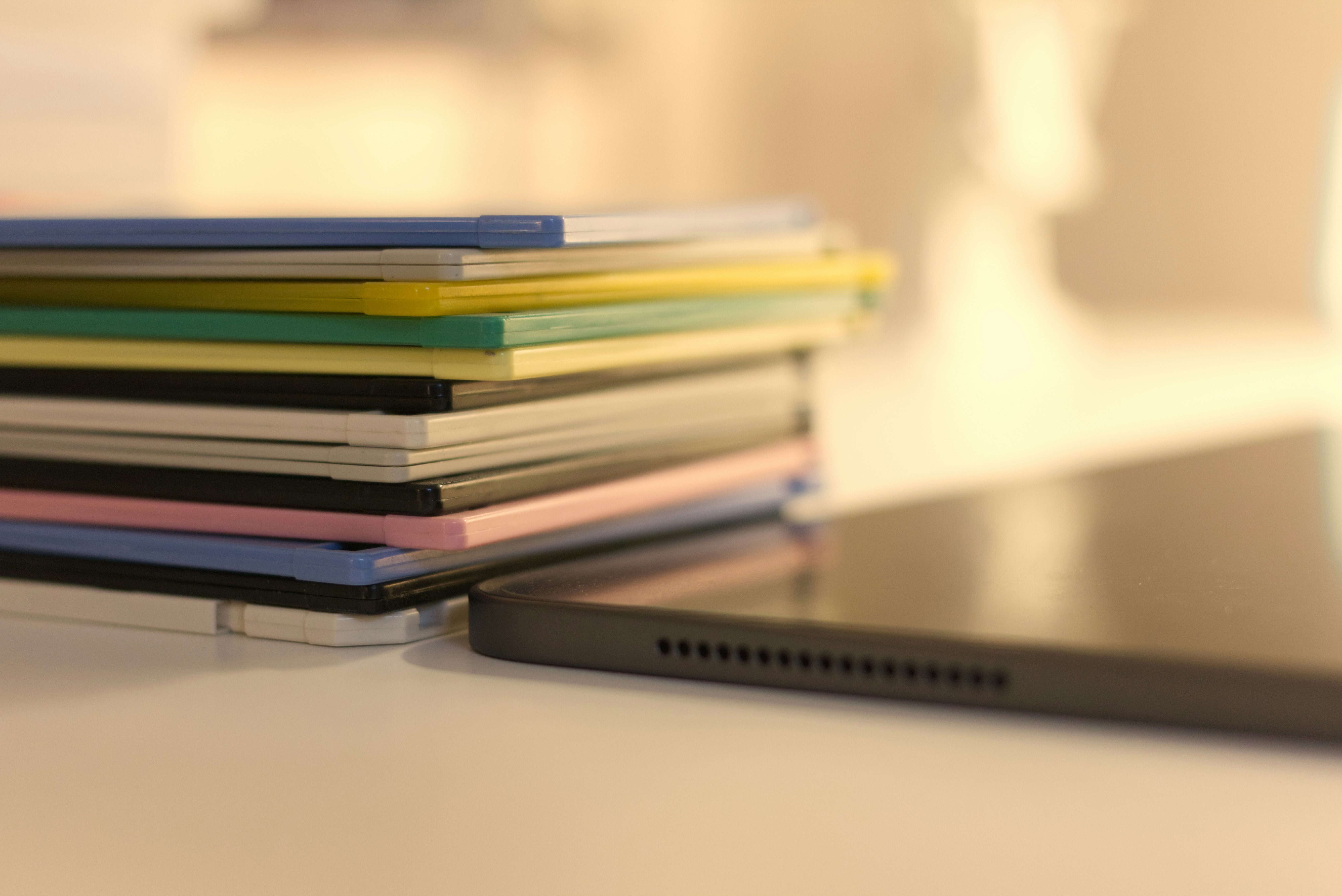 Uma pilha de livros multicoloridos está ao lado de um tablet moderno sobre uma superfície clara.